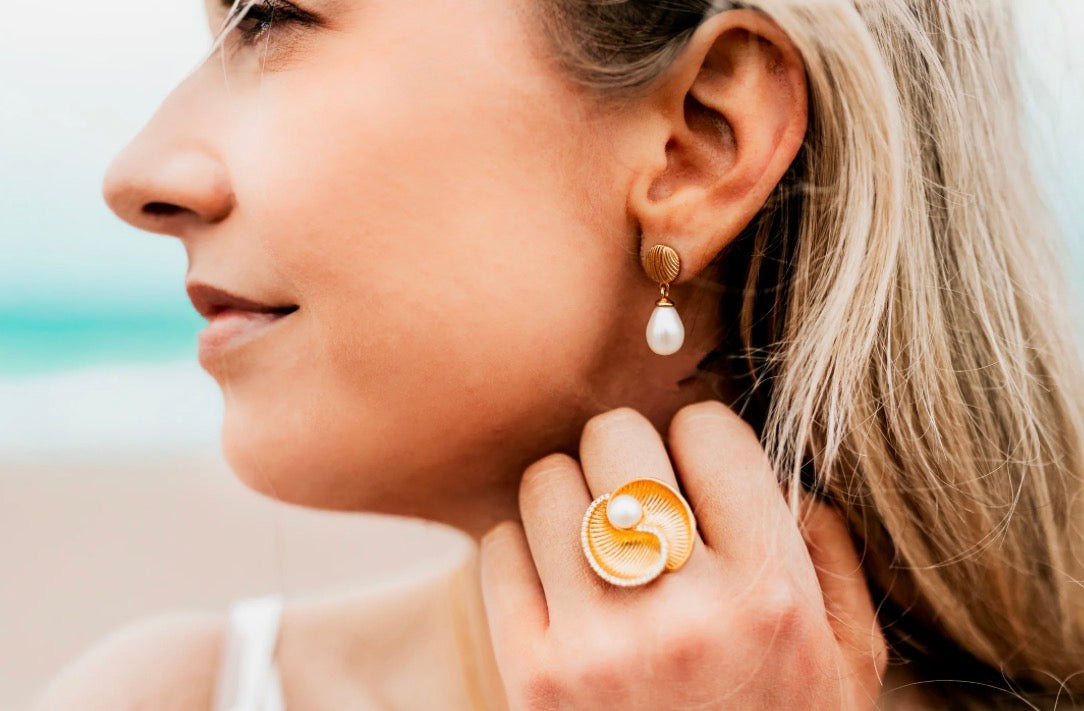 Gold shell and pearl short drop earrings featuring a polished gold-toned shell-shaped top with a single small round pearl dangling below, creating a minimal and elegant drop design.
