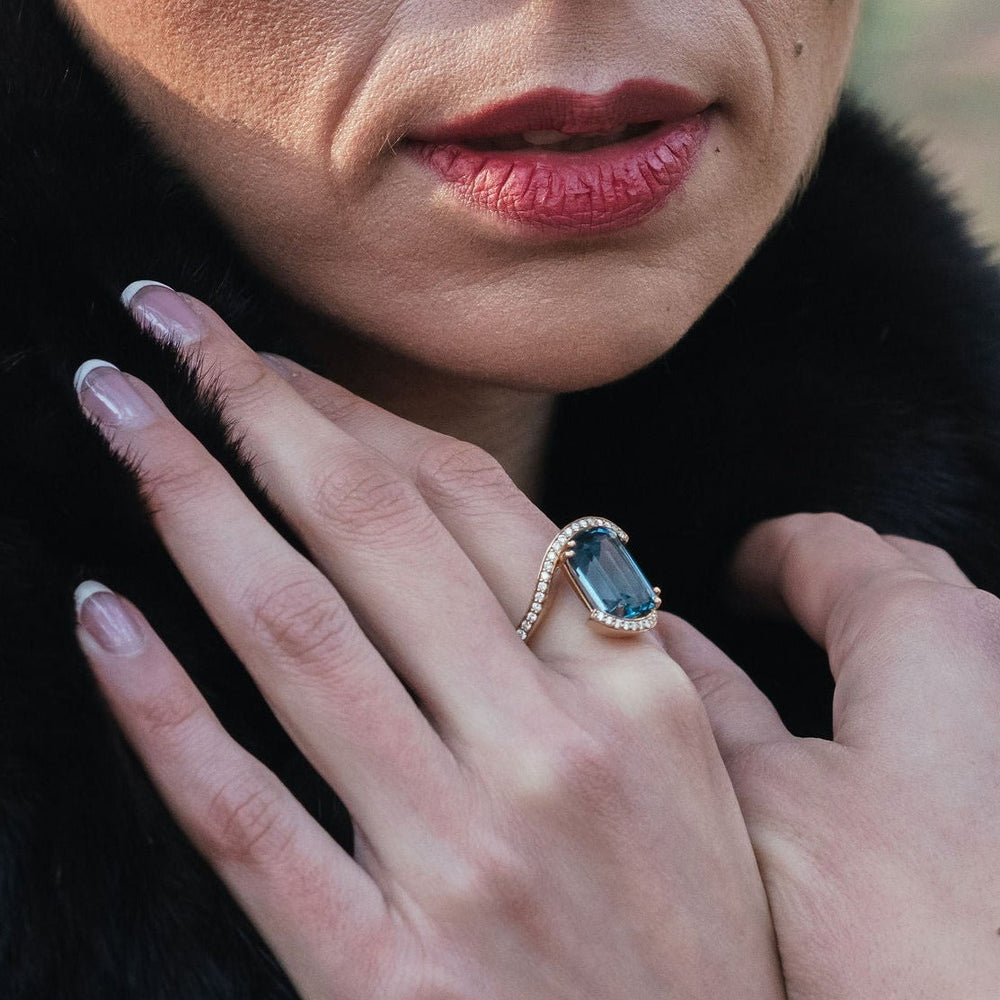 
                  
                    Model wearing diamond ring with teal topaz in wedeln design in 18ct yellow gold
                  
                