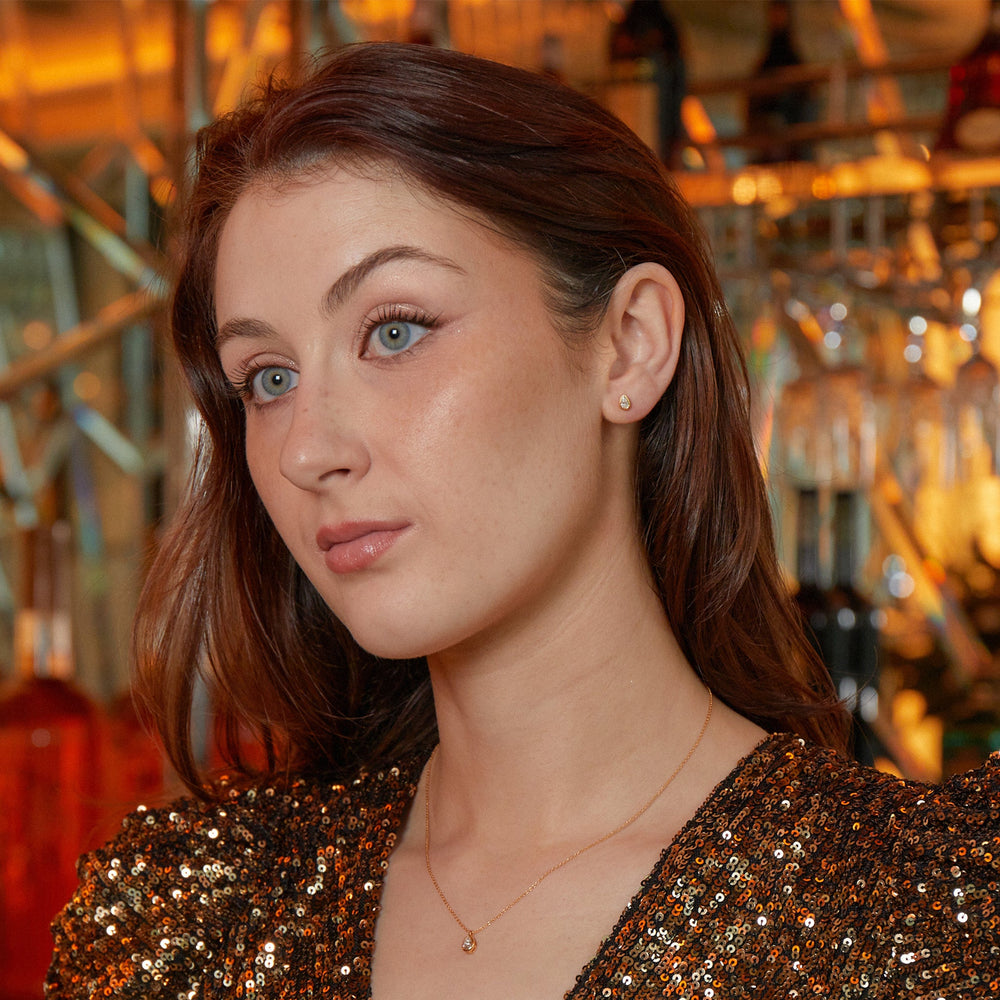 
                  
                    Model wearing New York Collection Delicate Pear Shaped Gold Diamond Stud Earrings Bezel Set with 0.25ct pear-cut diamonds from Augustine Jewels
                  
                